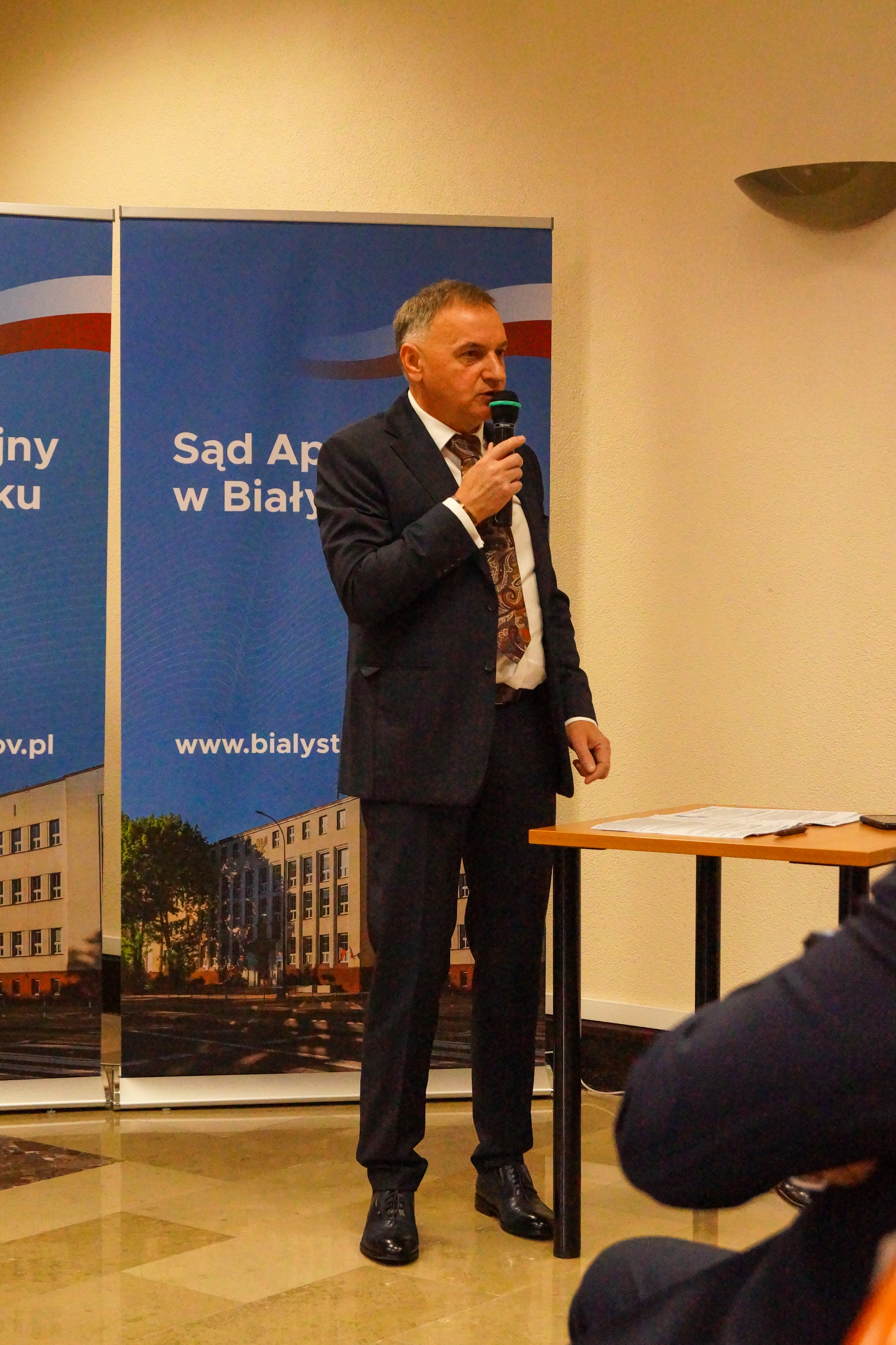 Zdjęcie przedstawia przemawiającego Marka Szymanowskiego Prezesa Sadu Apelacyjnego w Białymstoku na sali konferencyjnej.